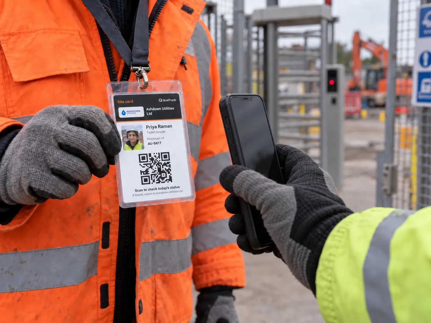 At a site gate, an operative in hi-vis holds out their site card while someone scans its QR code with a phone.